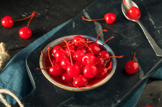A bowl of marashino cherries on a black marble cutting board as a visual representation of Maraschino Cherry Fragrance Oil available at Village Craft and Candle 