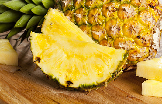 Pineapple slices with a full pineapple in the background as a visual representation of Pineapple Fragrance Oil available at Village Craft and Candle 