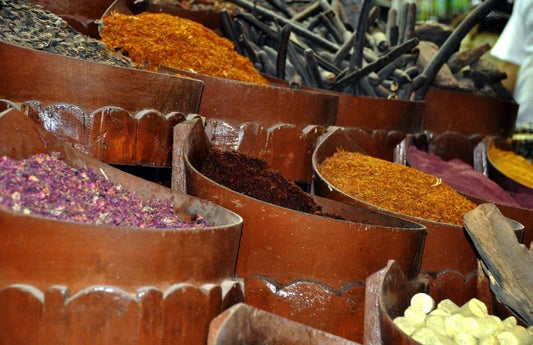  Vieux barils de diverses épices colorées sur un marché comme représentation visuelle de l'huile parfumée Rooibos Safran disponible chez Village Craft and Candle